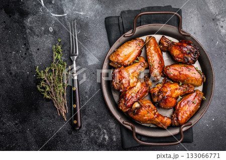 Savory grilled chicken wings smothered in tangy barbecue sauce, the ultimate treat for meat lovers and party enthusiasts. black background. top view 133066771