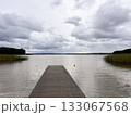 Wooden pier stretches into the lake under cloudy sky. 133067568