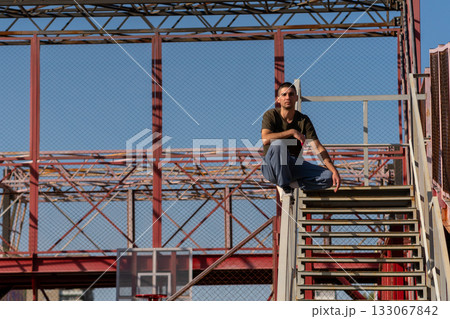 Man maintains crouched pose on stair rail in metal parkour zone 133067842