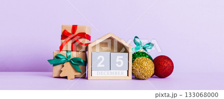 25 december. Christmas composition on colored background with a wooden calendar, with a gift box, toys, bauble copy space 133068000