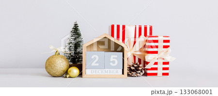 25 december. Christmas composition on colored background with a wooden calendar, with a gift box, toys, bauble copy space 25 december. Christmas composition on colored background with a wooden calendar, with a gift box, toys, bauble copy space 133068001