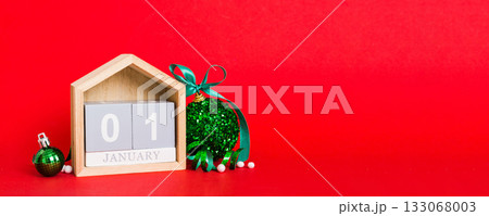 1 january. Christmas composition on colored background with a wooden calendar, with a gift box, toys, bauble copy space 1 january. Christmas composition on colored background with a wooden calendar, with a gift box, toys, bauble copy space 133068003