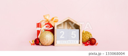 25 december. Christmas composition on colored background with a wooden calendar, with a gift box, toys, bauble copy space 133068004