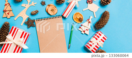 Top view of notebook on blue background made of Christmas decorations. New Year time concept Top view of notebook on blue background made of Christmas decorations. New Year time concept 133068064