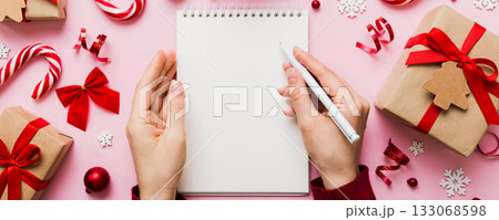 Woman writing Christmas to do list on notebook on colored background with xmas decorations 133068598