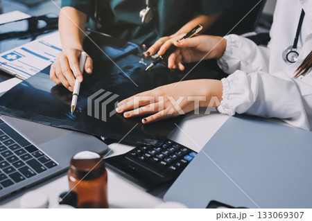 Group of doctors attending seminar in hospital lecture hall with senior physician giving medical presentation and professional training session on healthcare practices Group of doctors attending seminar in hospital lecture hall with senior physician giving medical presentation and professional training session on healthcare practices 133069307