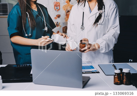 Group of doctors attending seminar in hospital lecture hall with senior physician giving medical presentation and professional training session on healthcare practices Group of doctors attending seminar in hospital lecture hall with senior physician giving medical presentation and professional training session on healthcare practices 133069316