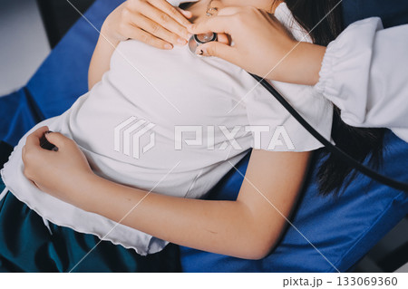 Doctor examining patient with stethoscope in hospital bed. Medical care and healthcare concept in a clinical setting. Doctor examining patient with stethoscope in hospital bed. Medical care and healthcare concept in a clinical setting. 133069360