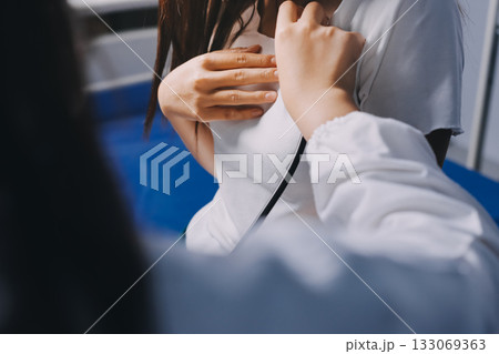 Doctor examining patient with stethoscope in hospital bed. Medical care and healthcare concept in a clinical setting. 133069363