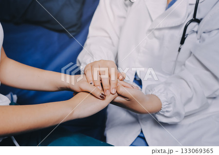 Doctor giving hope. Close up shot of young female physician leaning forward to smiling elderly lady patient holding her hand in palms. Woman caretaker in white coat supporting encouraging old person Doctor giving hope. Close up shot of young female physician leaning forward to smiling elderly lady patient holding her hand in palms. Woman caretaker in white coat supporting encouraging old person 133069365