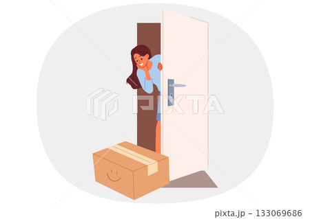 Woman rejoices at receiving package delivered by courier and looks out of apartment through door 133069686