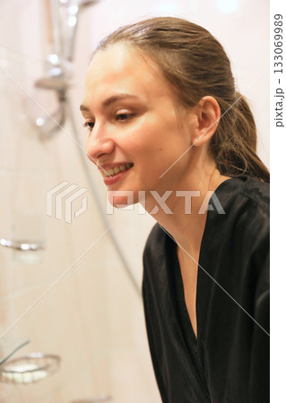 Woman Cleansing Face, Smiling In Bathroom Woman Cleansing Face, Smiling In Bathroom 133069989