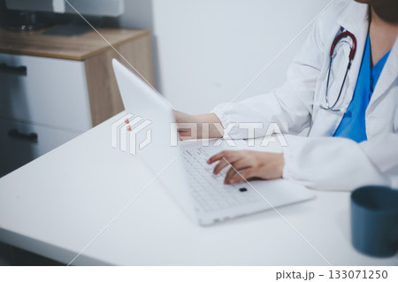 Middle aged female doctor working on laptop in doctor's room 133071250
