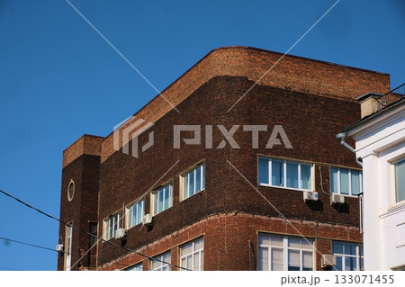 Old industrial brick building with rounded corners and rows of rectangular windows, featuring visible air conditioning units and weathered masonry. The image highlights durable early 20th-century 133071455