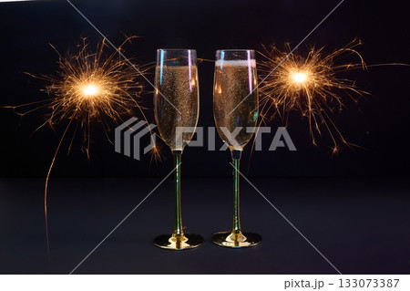 Sparkling Celebration. Two champagne glasses with bright sparklers against a dark background Sparkling Celebration. Two champagne glasses with bright sparklers against a dark background 133073387