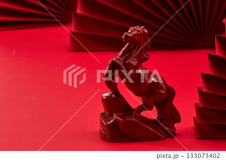 Red Horse Sculpture. Wooden horse figurine on a red background with folded paper decor. Red Horse Sculpture. Wooden horse figurine on a red background with folded paper decor. 133073402