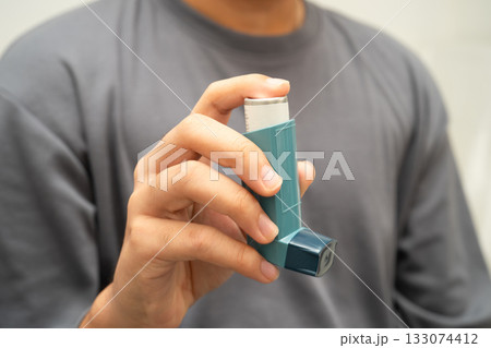 Asthma and chronic obstructive pulmonary disease COPD, Asian young man using metered dose inhaler MDI. 133074412
