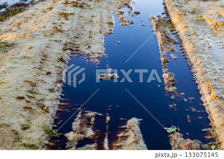 Dark, polluted water sits in a muddy area, showing the impact of waste and toxic materials on the environment 133075145