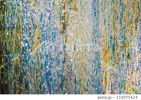 Close-up of metallic tinsel strands in gold, silver, and blue shimmering under festive lighting. Retro tinsel revival, vintage Christmas style, nostalgic 80s decor, old-school holiday glam 133075424