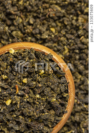 aromatic tea with the addition of dried ripe peach fruits in a wooden bowl , dried high-quality leaf tea poured into a bowl with natural flavors and a piece of ripe natural fruits 133075609