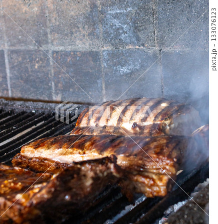 Grilling succulent short ribs and other cuts of red meat over hot coals on an authentic argentinian parrilla, creating a delicious aroma and a traditional barbecue experience Grilling succulent short ribs and other cuts of red meat over hot coals on an authentic argentinian parrilla, creating a delicious aroma and a traditional barbecue experience 133076123