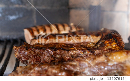 Juicy argentine barbecue meat grilling on a charcoal parrillada, preparing delicious cuts of beef and chorizo for a traditional outdoor meal, fresh food cooking Juicy argentine barbecue meat grilling on a charcoal parrillada, preparing delicious cuts of beef and chorizo for a traditional outdoor meal, fresh food cooking 133076124