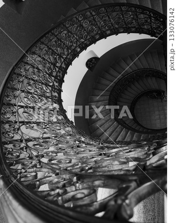 Black and white spiral staircase with ornate iron railing viewed from above 133076142