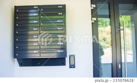 System of metal mailboxes with locks near the entrance of a residential apartment building. Urban housing detail in daylight.  133076628