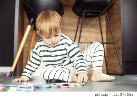 A cute two-year-old boy is playing happily in a bright, cozy room. The toddler is full of energy and curiosity, enjoying imaginative play and discovering new things. Perfect image for illustrating A cute two-year-old boy is playing happily in a bright, cozy room. The toddler is full of energy and curiosity, enjoying imaginative play and discovering new things. Perfect image for illustrating 133076652