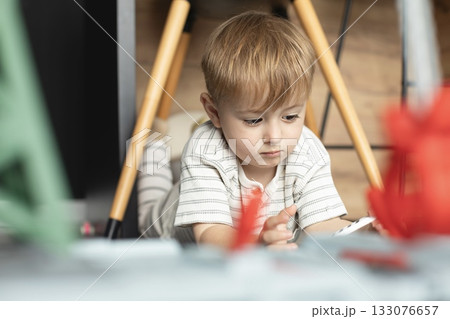 A cute two-year-old boy is playing happily in a bright, cozy room. The toddler is full of energy and curiosity, enjoying imaginative play and discovering new things. Perfect image for illustrating A cute two-year-old boy is playing happily in a bright, cozy room. The toddler is full of energy and curiosity, enjoying imaginative play and discovering new things. Perfect image for illustrating 133076657