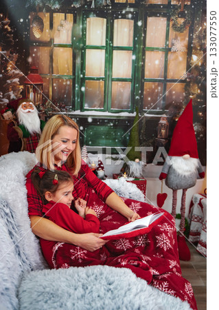 Mother daughter reading Christmas story cozy at home 133077550