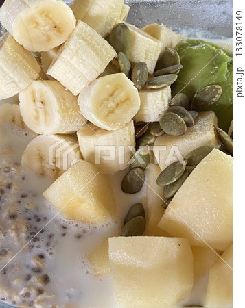 Bowl of oatmeal with banana, pumpkin seeds, chia seeds and milk, top view 133078149