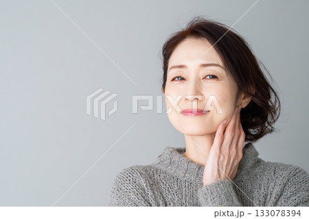 ミドル女性のエイジングケア　頬に手を添えて肌のハリを確認する笑顔 133078394