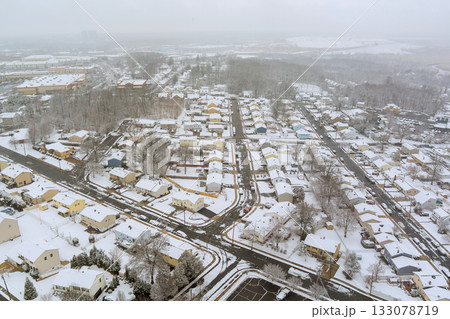 Snow blankets residential neighborhood in winter, creating serene quiet atmosphere across snowy town Snow blankets residential neighborhood in winter, creating serene quiet atmosphere across snowy town 133078719
