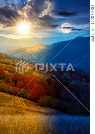 mountain landscape of countryside on autumn equinox. day and night time change concept. beautiful view of range with dappled light on forested slopes in colorful foliage with sun and moon at twilight 133079488