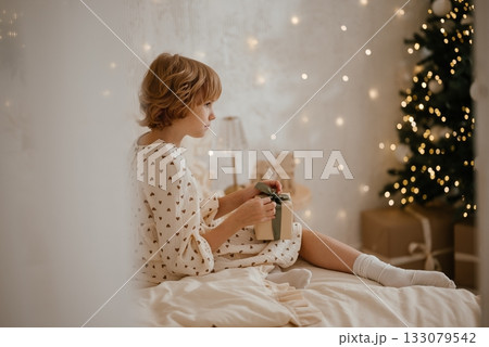 Child with Gift Box Amid Christmas Tree Decorations Child with Gift Box Amid Christmas Tree Decorations 133079542