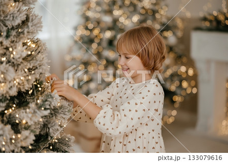 Child Decorating Christmas Tree with Joyful Expression Child Decorating Christmas Tree with Joyful Expression 133079616