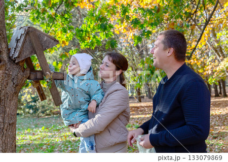 Happy family at the bird feeder. 133079869