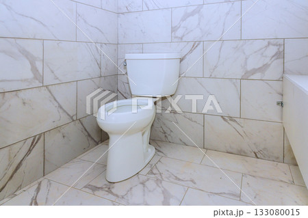 Modern white toilet in stylish marble bathroom with clean tiles spacious layout Modern white toilet in stylish marble bathroom with clean tiles spacious layout 133080015