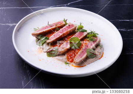 Seared Tuna Steak Slices on Creamy Sauce with Fresh Greens 133080258