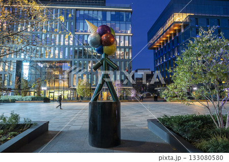 An evening view of a business center with modern glass and steel architecture and a square with a flowerbed next to it. An evening view of a business center with modern glass and steel architecture and a square with a flowerbed next to it. 133080580