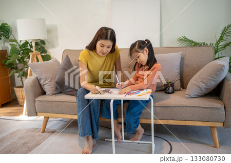 Lovely mom and little young daughter spending time together in their living room. Lovely mom and little young daughter spending time together in their living room. 133080730
