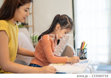 Lovely mom and little young daughter spending time together in their living room. Lovely mom and little young daughter spending time together in their living room. 133080738