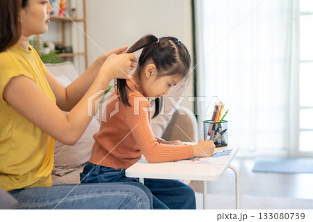 Lovely mom and little young daughter spending time together in their living room. Lovely mom and little young daughter spending time together in their living room. 133080739