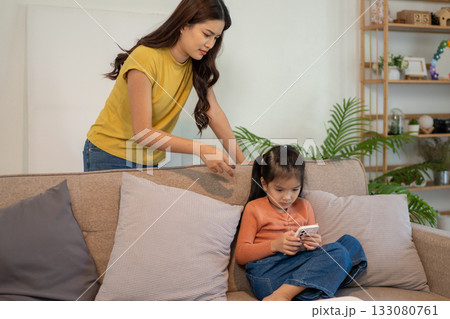 Lovely mom and little young daughter spending time together in their living room. Lovely mom and little young daughter spending time together in their living room. 133080761