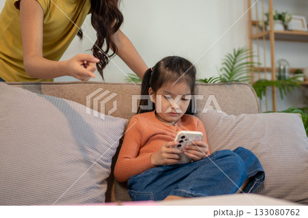 Lovely mom and little young daughter spending time together in their living room. 133080762