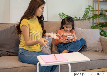Lovely mom and little young daughter spending time together in their living room. Lovely mom and little young daughter spending time together in their living room. 133080763