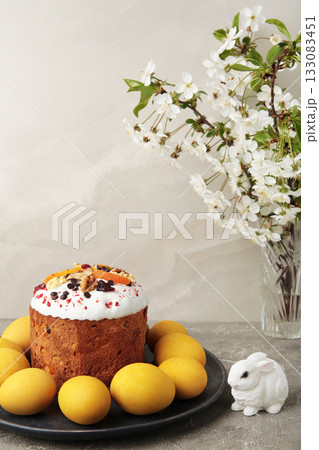 Traditional easter cakes with colorful sprinkles, with eggs, a bunny figurine, and spring flowers, creating a festive holiday scene. Vertical photo Traditional easter cakes with colorful sprinkles, with eggs, a bunny figurine, and spring flowers, creating a festive holiday scene. Vertical photo 133083451