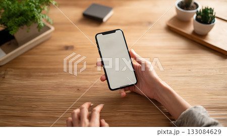 Person holding smartphone with financial transaction screen open. Mobile banking, digital finance and online payments in clean workspace setting 133084629