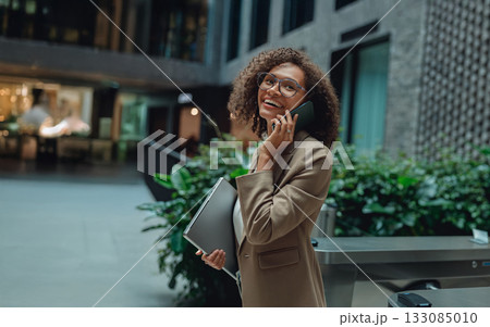 woman with briefcase walking confidently, businesswoman holding folder while chatting on phone during journey woman with briefcase walking confidently, businesswoman holding folder while chatting on phone during journey 133085010
